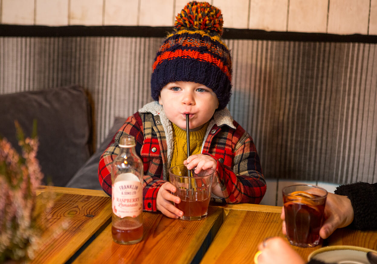 Young child drinking raspberry lemonade through a straw